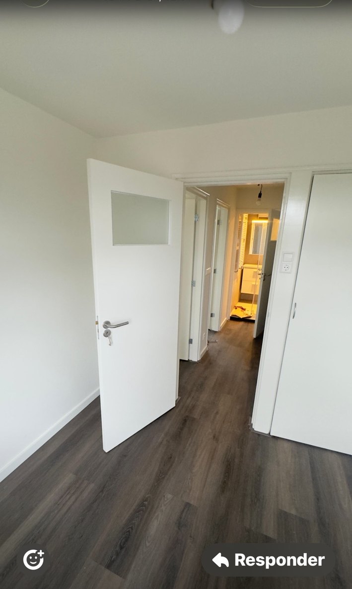 Witte binnendeur en grijze laminaatvloer in een afgewerkte gang