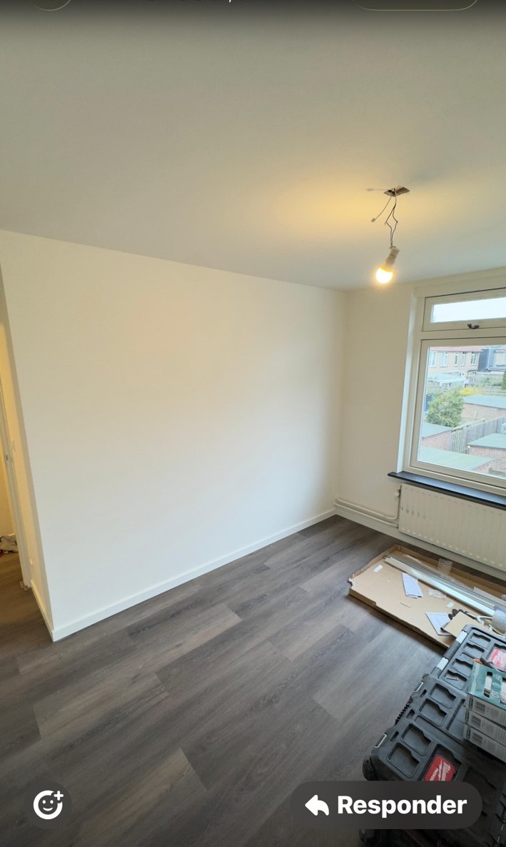 Grijze laminaatvloer in een opgefriste kamer met lichte wanden